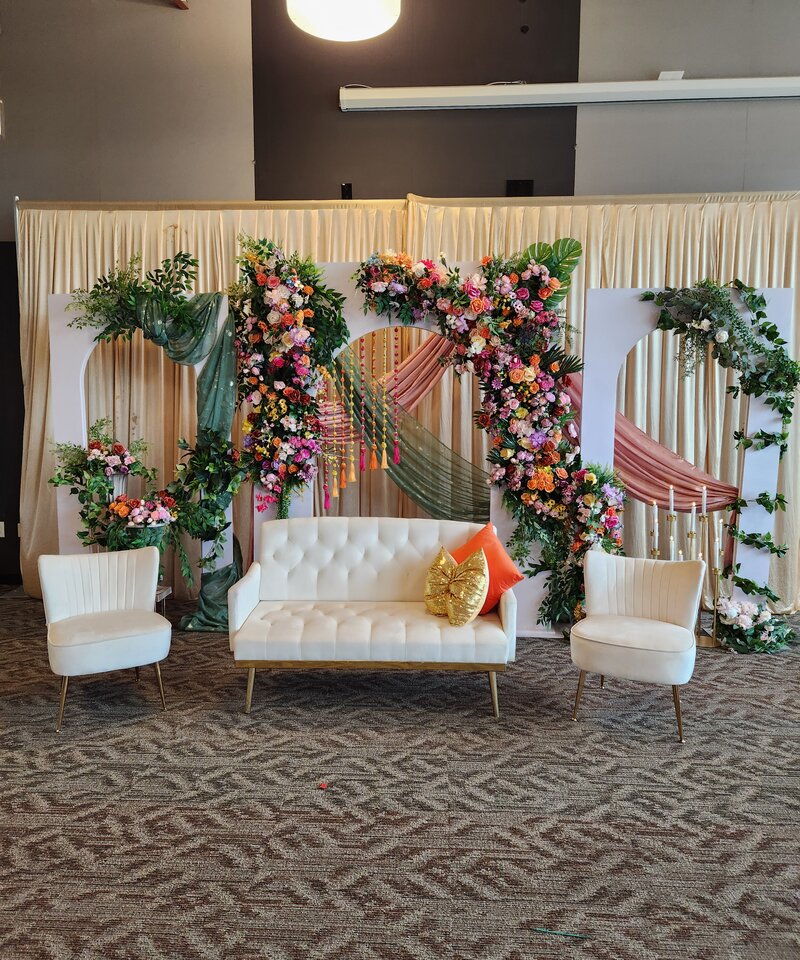 Colorful bohemian Mehndi stage with tropical florals and sage draping South Asian wedding Ohio