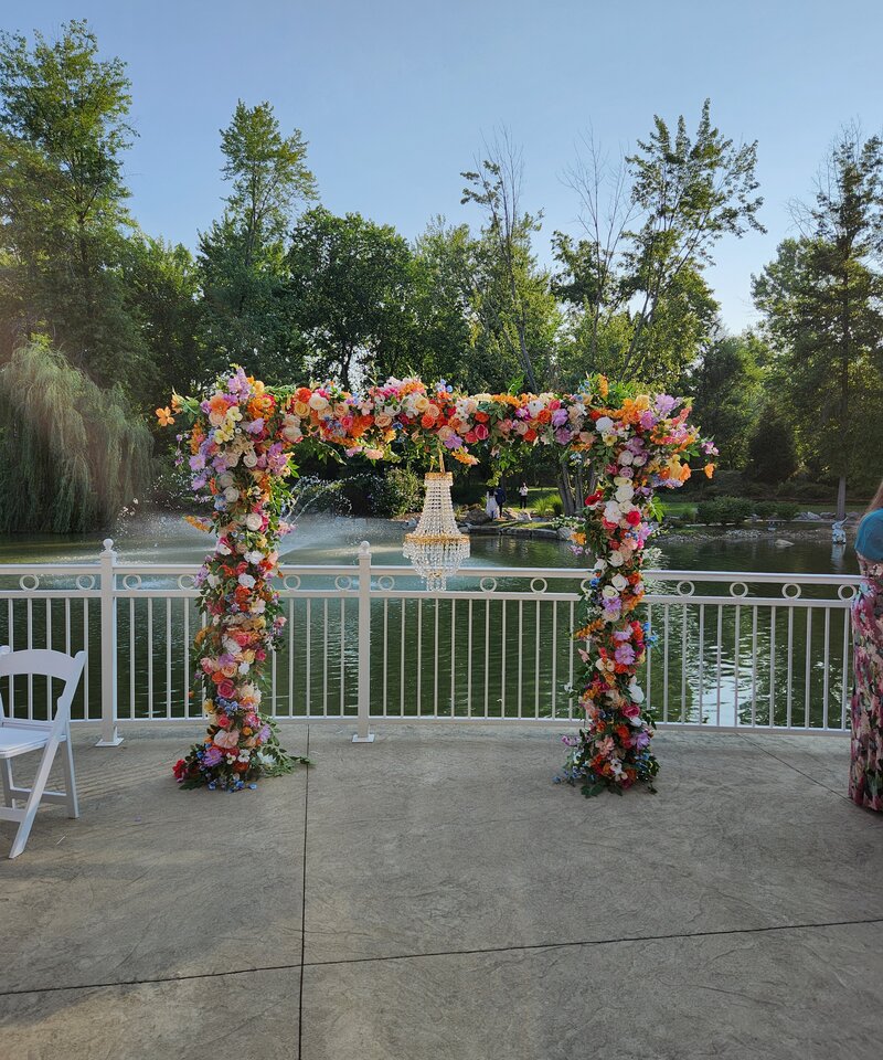 Outdoor lakeside wedding ceremony colorful floral arch with crystal chandelier Ohio