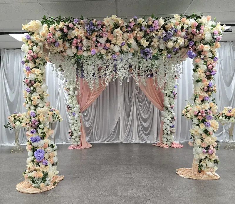 Four-post floral canopy covered in pastel roses with hanging wisteria and blush draping by Events By Maryam