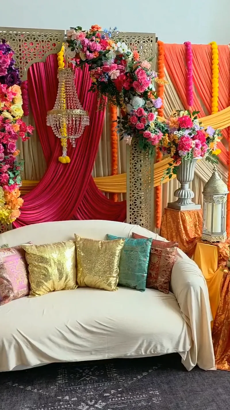Colorful candlelit celebration stage with gold cushions and florals by Events By Maryam