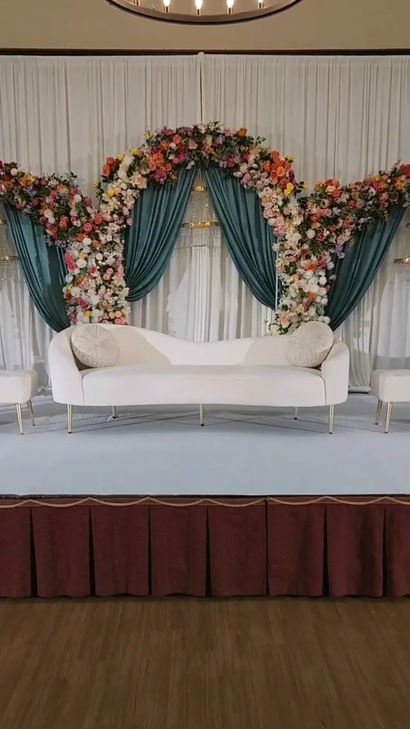 Teal drapery floral arch stage with white sofa by Events By Maryam