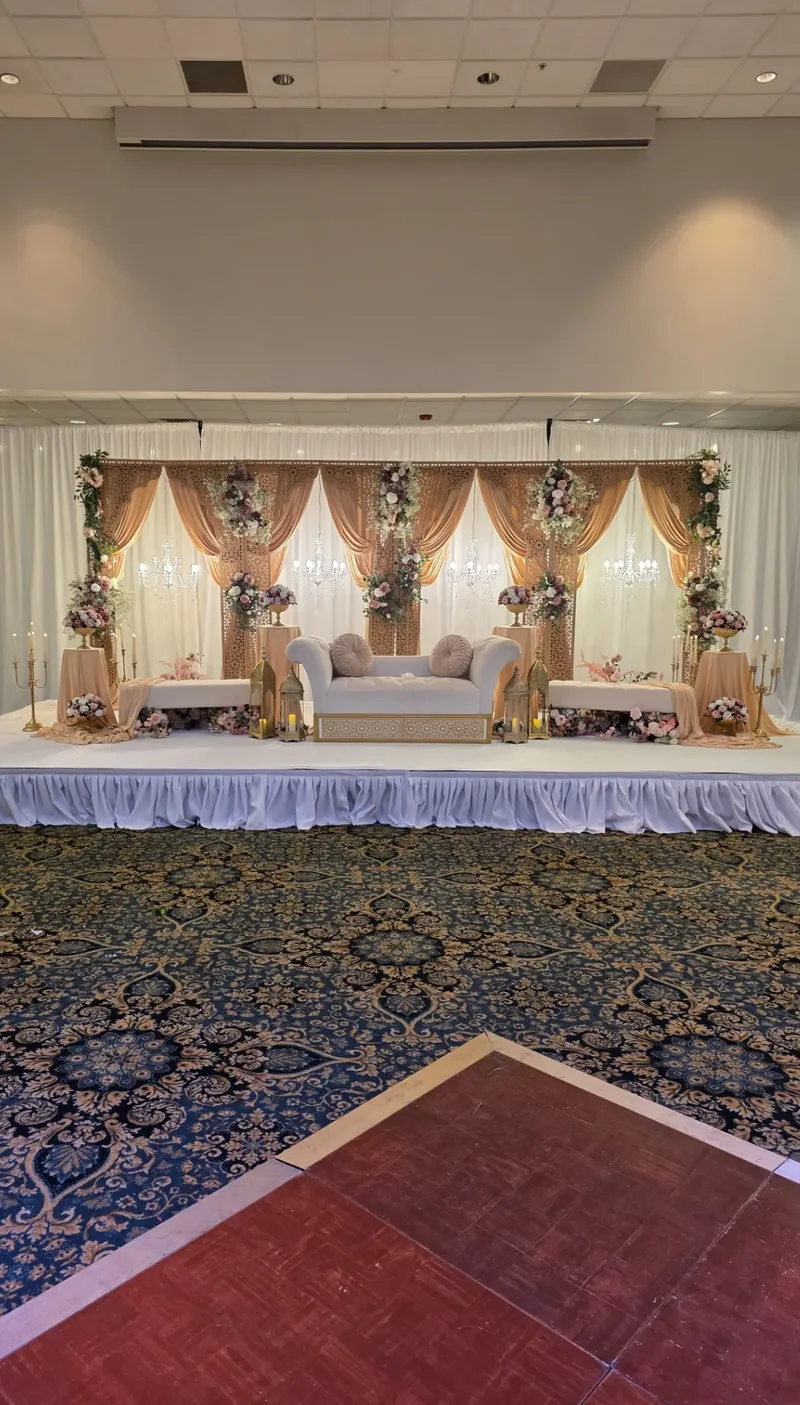 Blush and gold jali-panel reception stage with crystal chandeliers, lanterns and florals by Events By Maryam