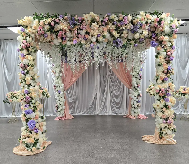 Four-post floral canopy covered in pastel roses with hanging wisteria and blush draping by Events By Maryam
